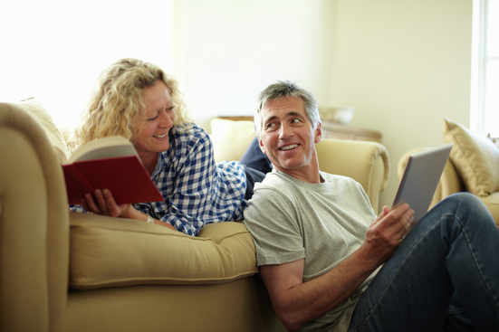 causual middle-aged couple in living room reading and looking at tablet