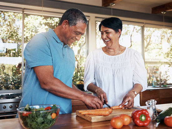 A mature couple making salad together in their kitchen.