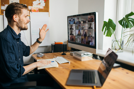 Man taking notes while attending remote digital meeting at work