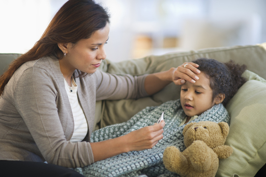 mother taking temperature of a sick child at home