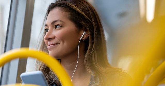 Woman with ear buds sitting on a public bus