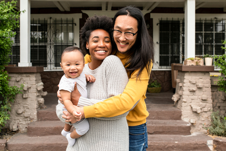 mom and dad holding baby in front of their house
