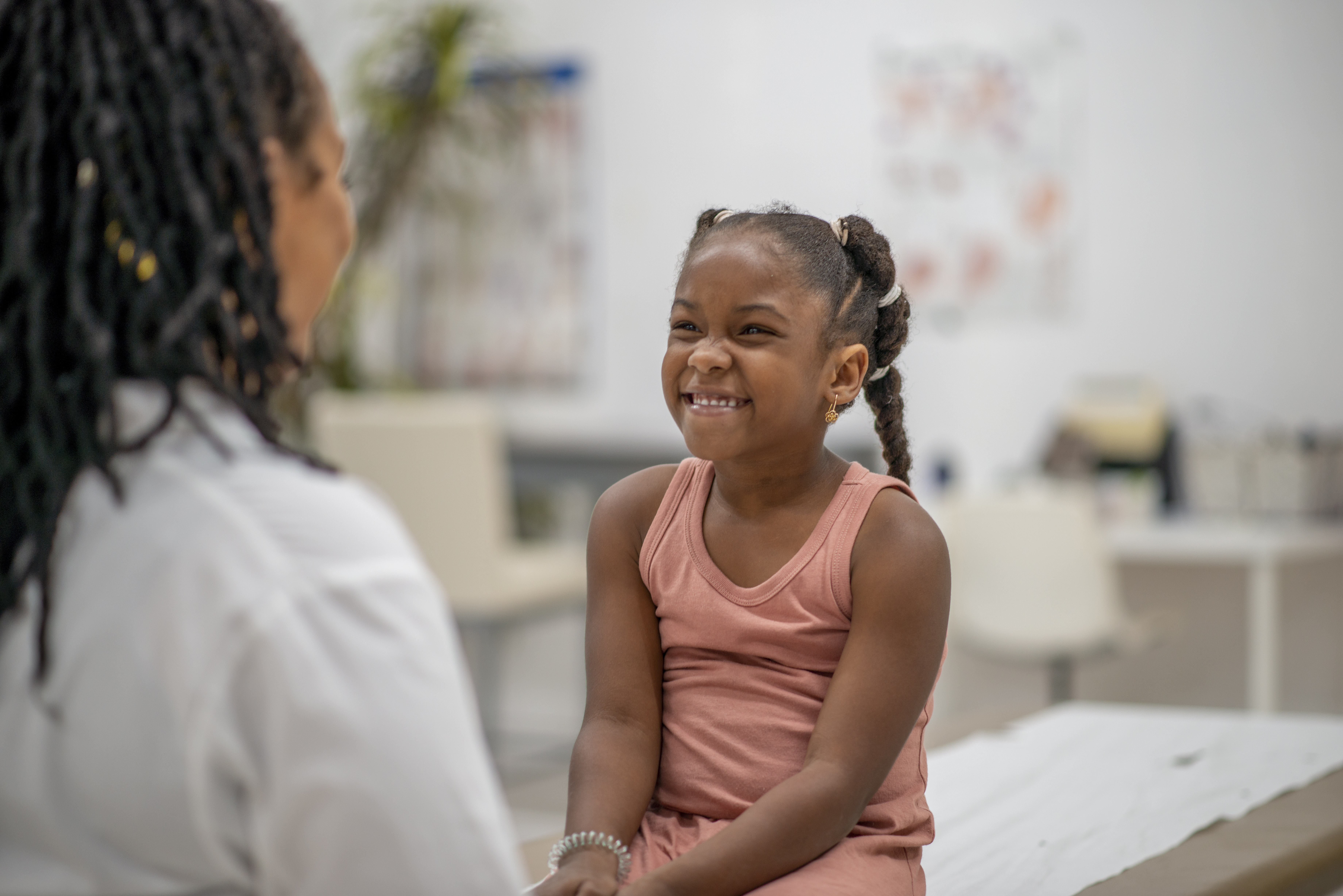 Girl sitting on doctor's table smiling at physician
