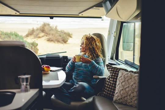 Woman relaxing drinking coffee looking out front window of motorhome