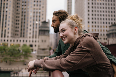 young couple looking out at city resting on handrail