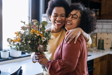 Mom giving her mom a flower bouquet while hugging