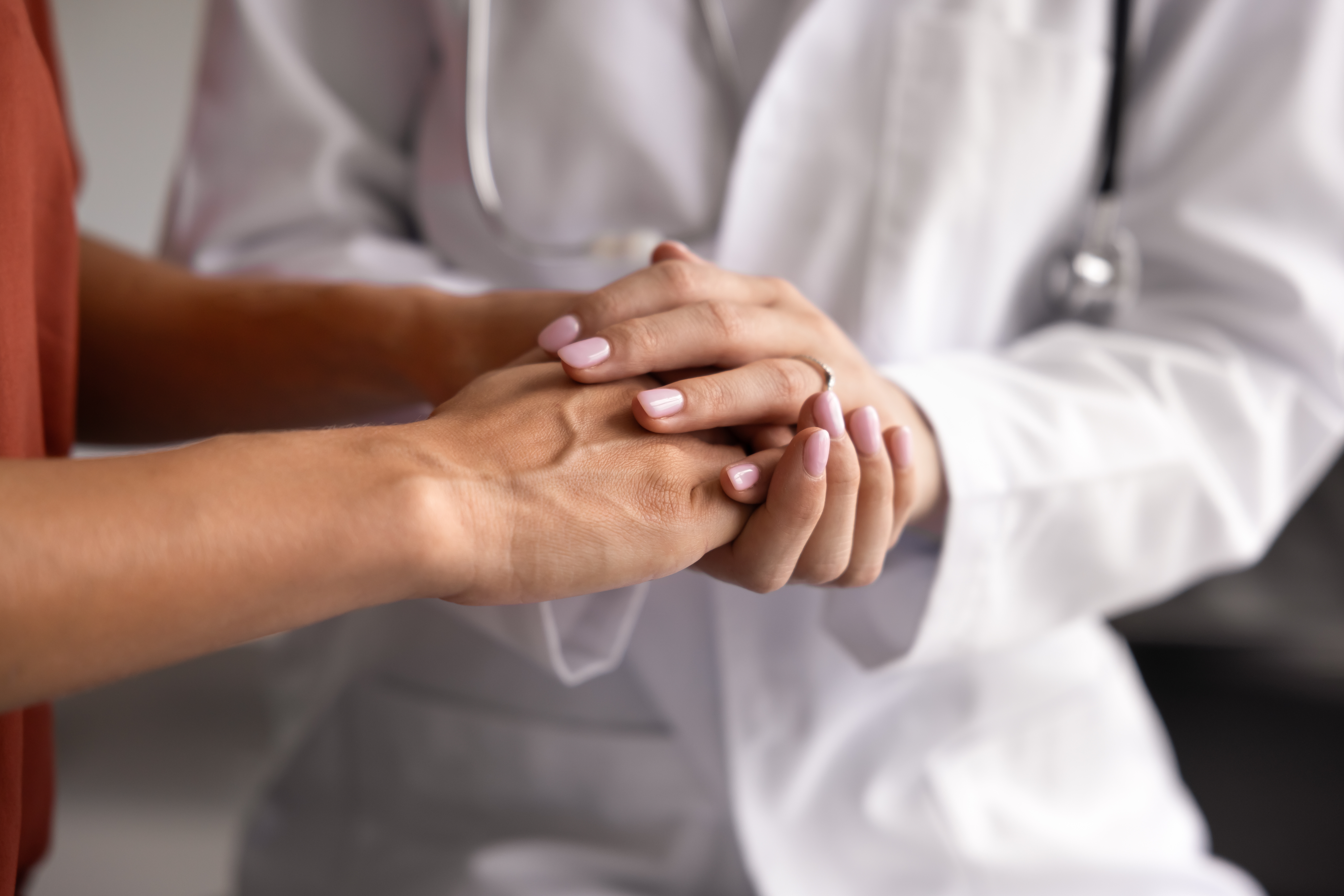 A close up of a female doctor holding a female patient's hands