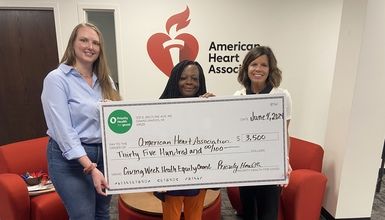 three people holding large check