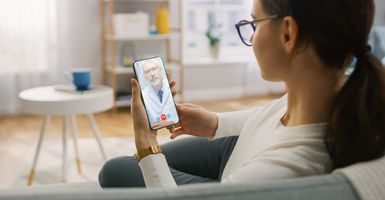 Woman having virtual doctor appointment at home on phone