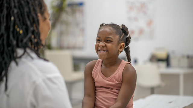 Girl sitting on doctor's table smiling at physician