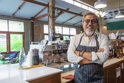 older smiling man working in coffee shop