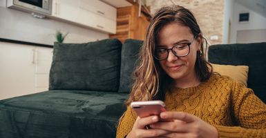 young woman sitting on floor looking at cell phone