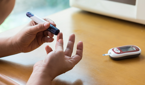 Person sitting at home using a blood sugar monitor