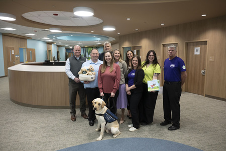 Team of personnel standing behind golden lab service dog
