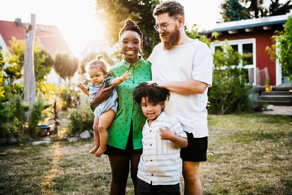 mom and dad with two young kids in front yard of home