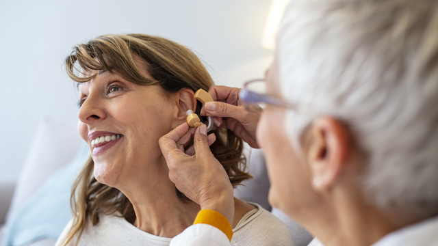 a smiling woman having a hearing aid fitted