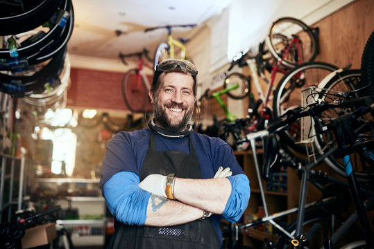 smiling man with crossed arms in bicycle repair shop