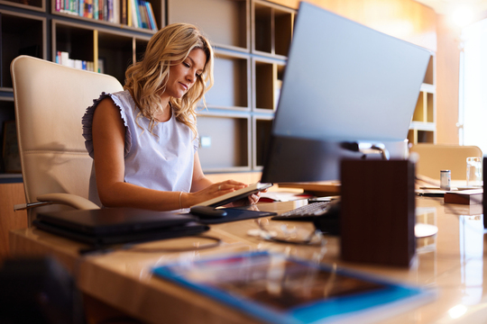 woman reading book at office desk