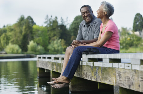 couple sitting on a dock with bare feet dangling