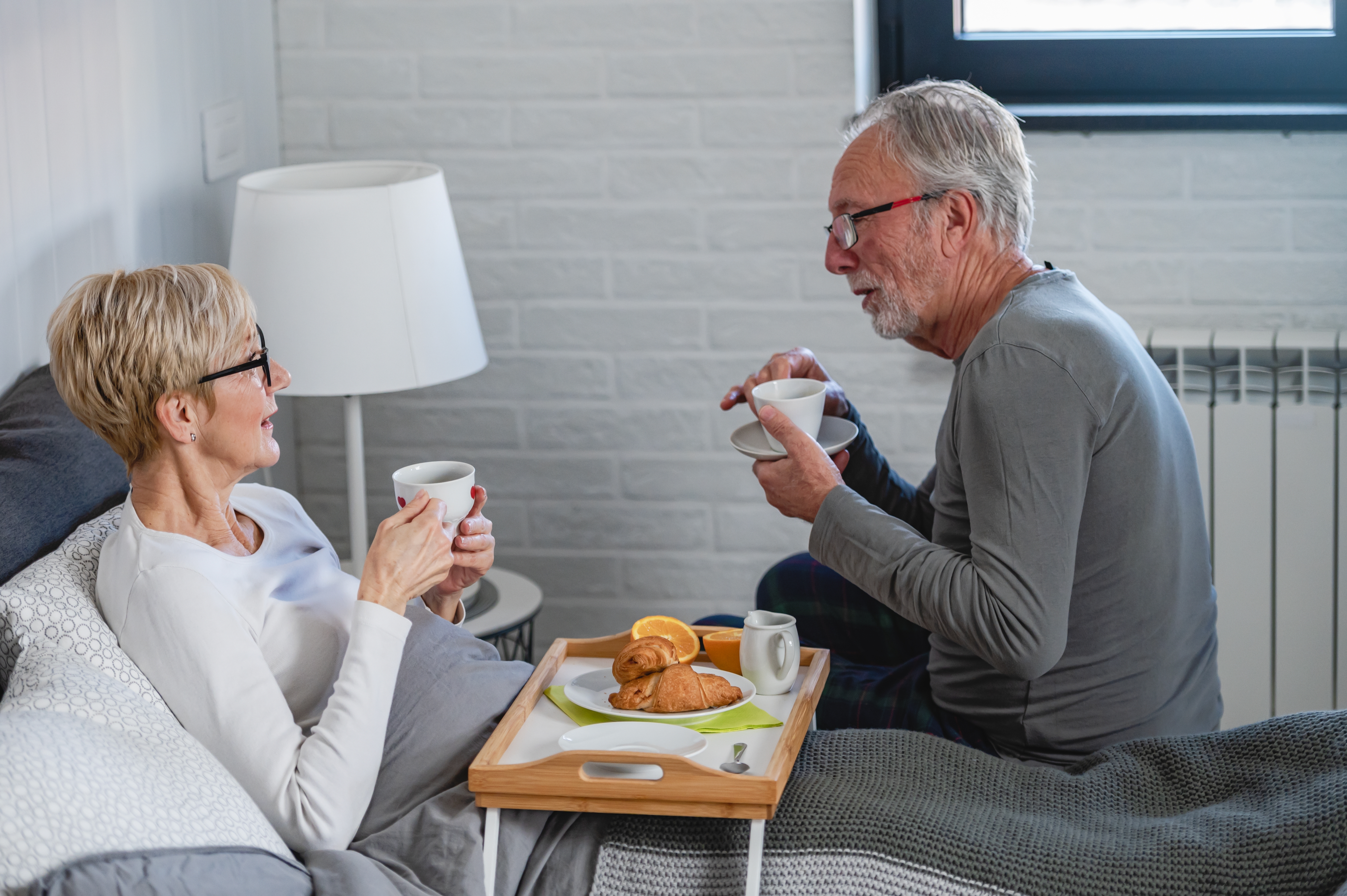 older white couple enjoy coffee and a meal in bed