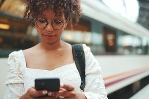 Woman standing next to train looking at cell phone