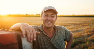 older man standing in field by his tractor