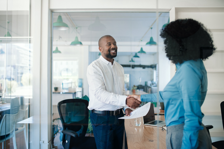two co-workers shaking hands in a bright office
