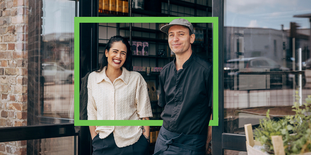 small business owners smiling at store front