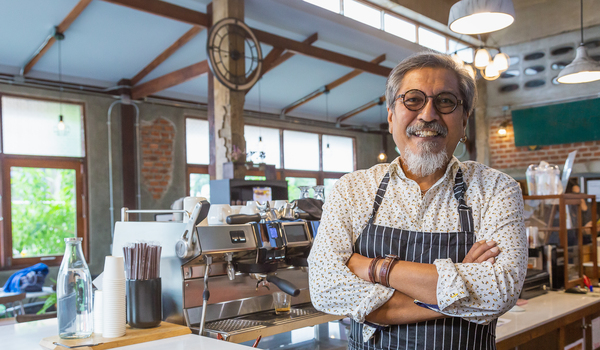 older smiling man working in coffee shop as barista