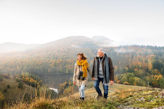 older couple summiting a hill with binoculars