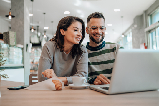 Young couple looking at a laptop while at a coffee shop