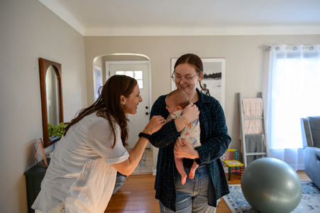 two women cuddle an infant in their living room