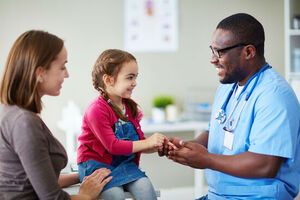 doctor talking to young patient and her mom