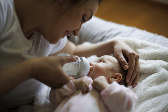 a woman bottle-feeding a baby