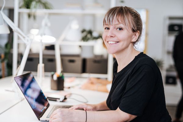 Smiling woman working on laptop at modern desk