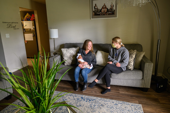 a new mother holds her infant on the couch