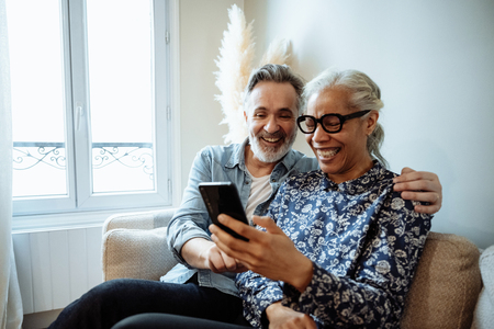 couple sitting close togehter on couch, laughing at phone screen image