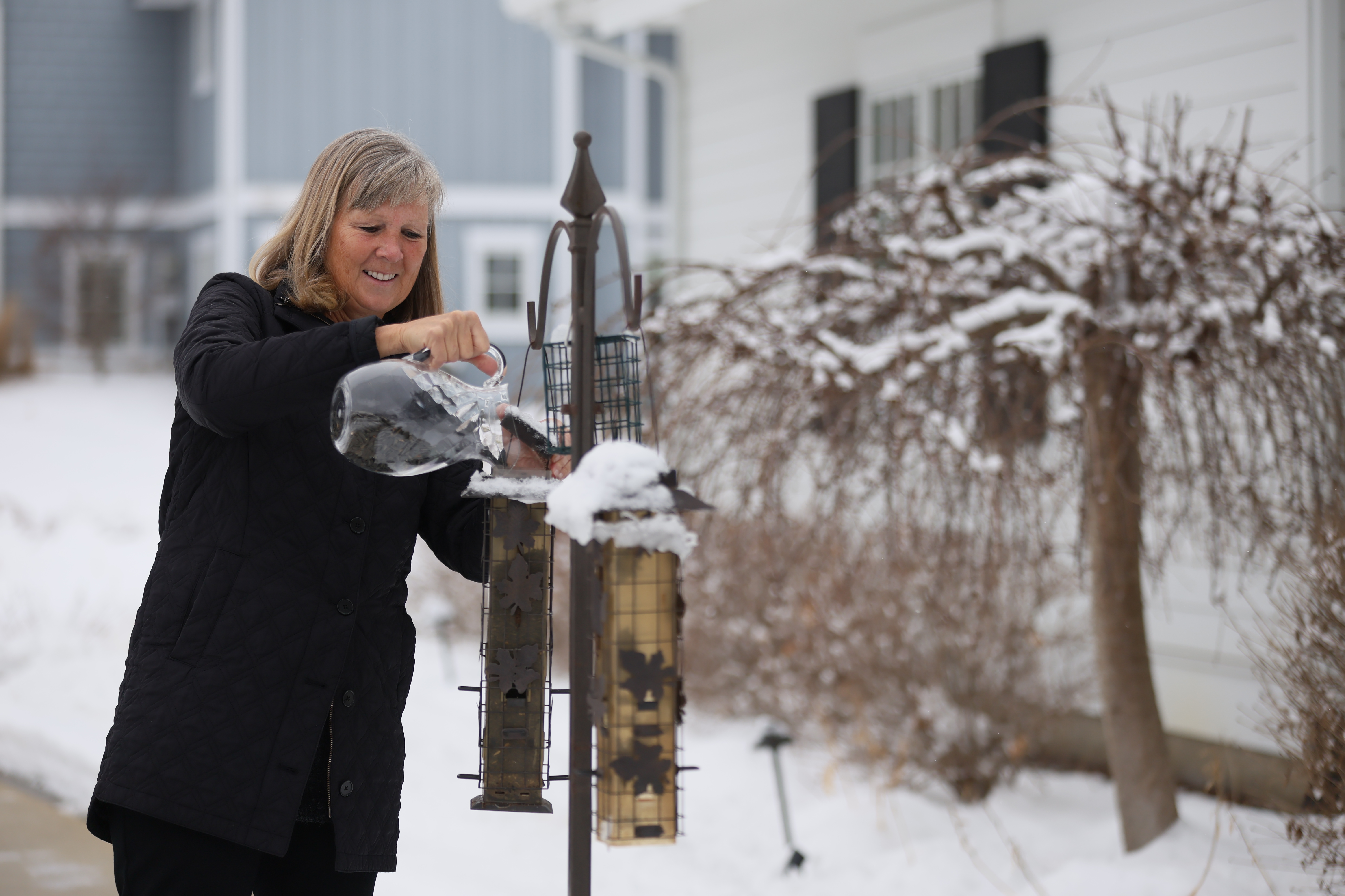 Karen filling her bird feeders on a winter day