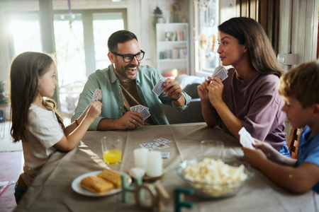 family of 4 playing cards around kitchen table
