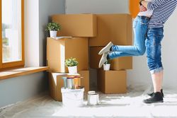 Couple embracing in new home with half-painted walls and moving boxes