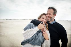 smiling middle age couple wearing sweaters hugging 