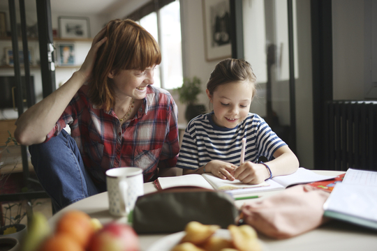 mom sitting at table with daughter helping with homework