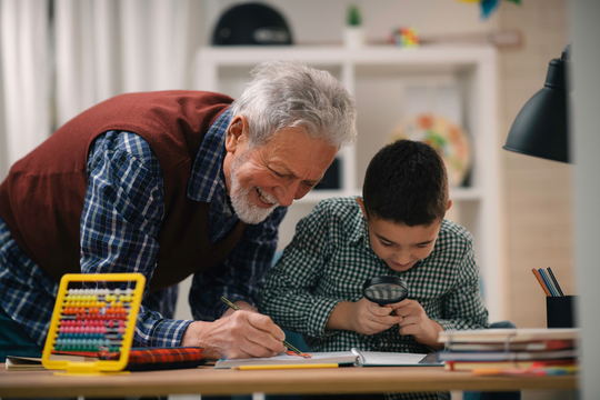 smiling grandfather helping grandson homework