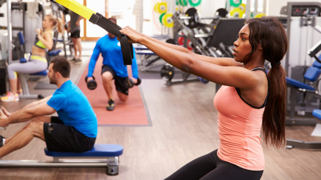 Multiple people using fitness equipment at a gym
