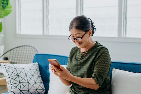 Smiling woman looking at smartphone in living room 