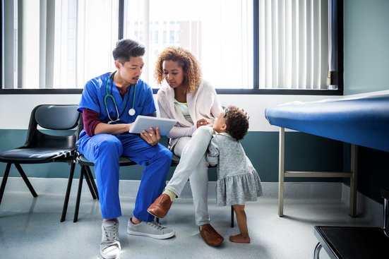healthcare worker with mom and young child in exam room looking at tablet
