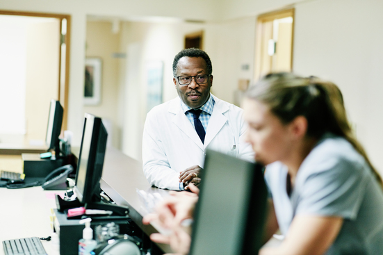healthcare workers at hospital desk with computers and phones