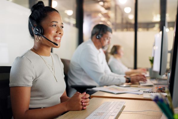 Woman with a headset sitting at a computer desk