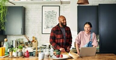 Man in plaid flannel with girl in overalls cooking in kitchen