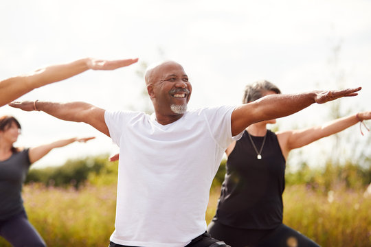 older adults doing mountain pose in outdoor yoga class